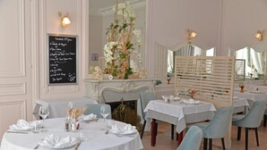 Un restaurante con mesas redondas, sillas azul claro y un menú en la pared.