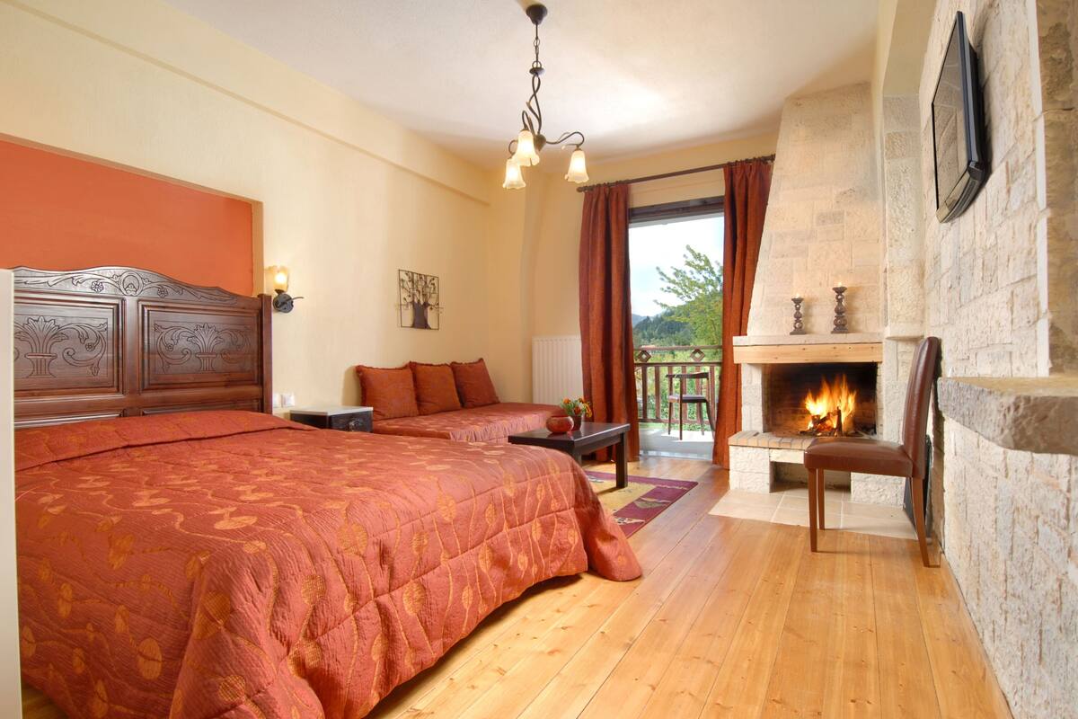 A bedroom with two beds, a fireplace, and a balcony with curtains.