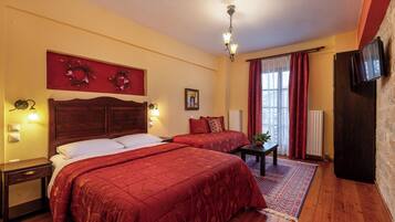 A hotel room with two beds, a wooden headboard, a red wall decoration, a small table, and a TV mounted on the wall.