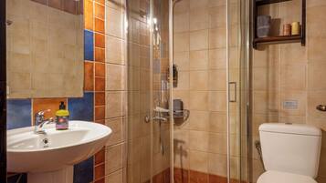 Un baño con ducha envuelta en vidrio, un lavamanos y un inodoro.