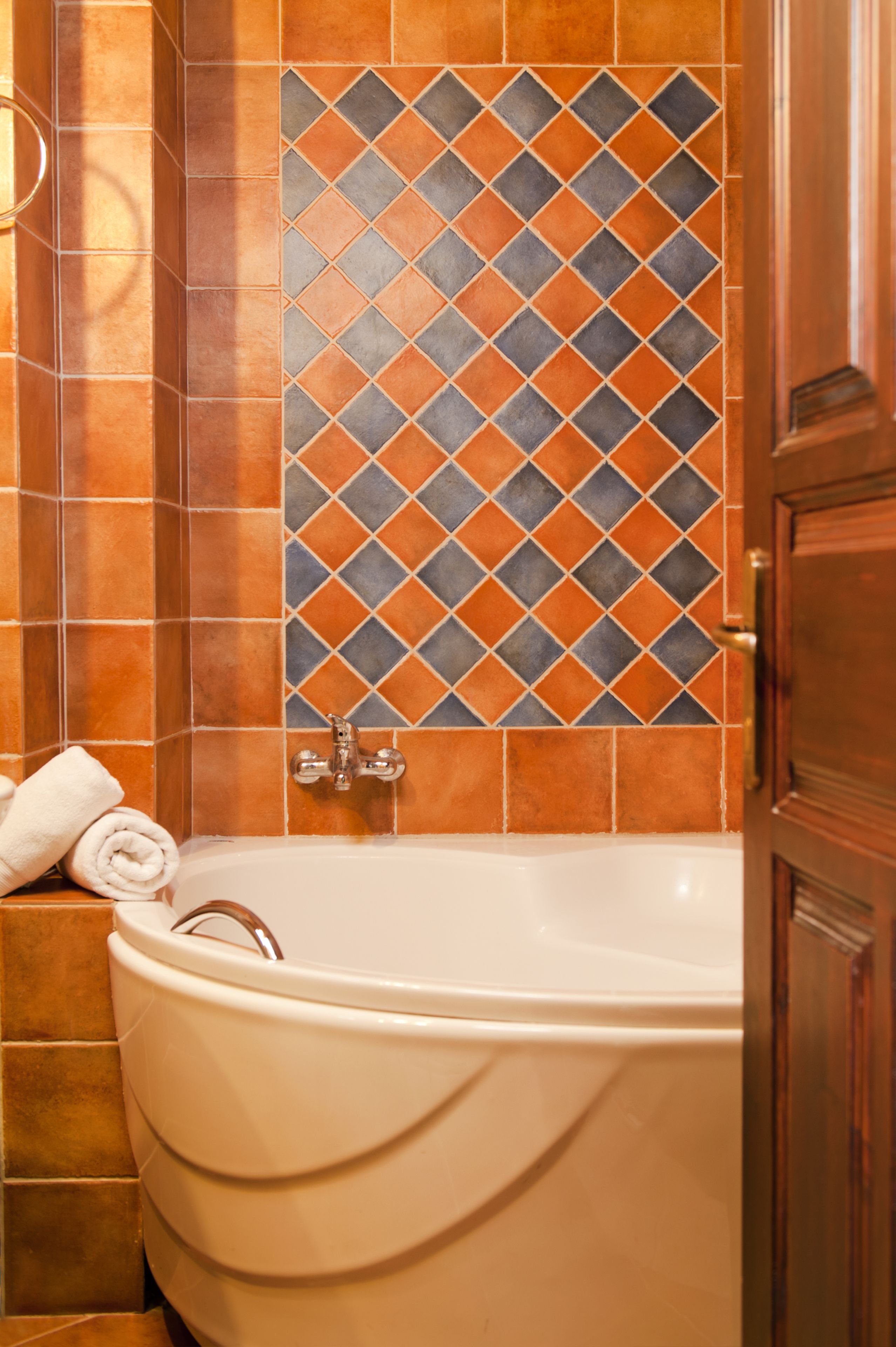 A bathroom with a bathtub, a towel, and a tiled wall.
