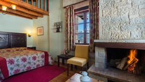 A cozy room with a bed, a chair, a table with a lantern, and a fireplace. - Mikri Arktos (Pyli)