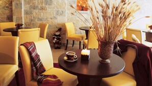 A cozy seating area with a round table, a vase of dried wheat stalks, a teddy bear, and a candle. - Mikri Arktos (Pyli)
