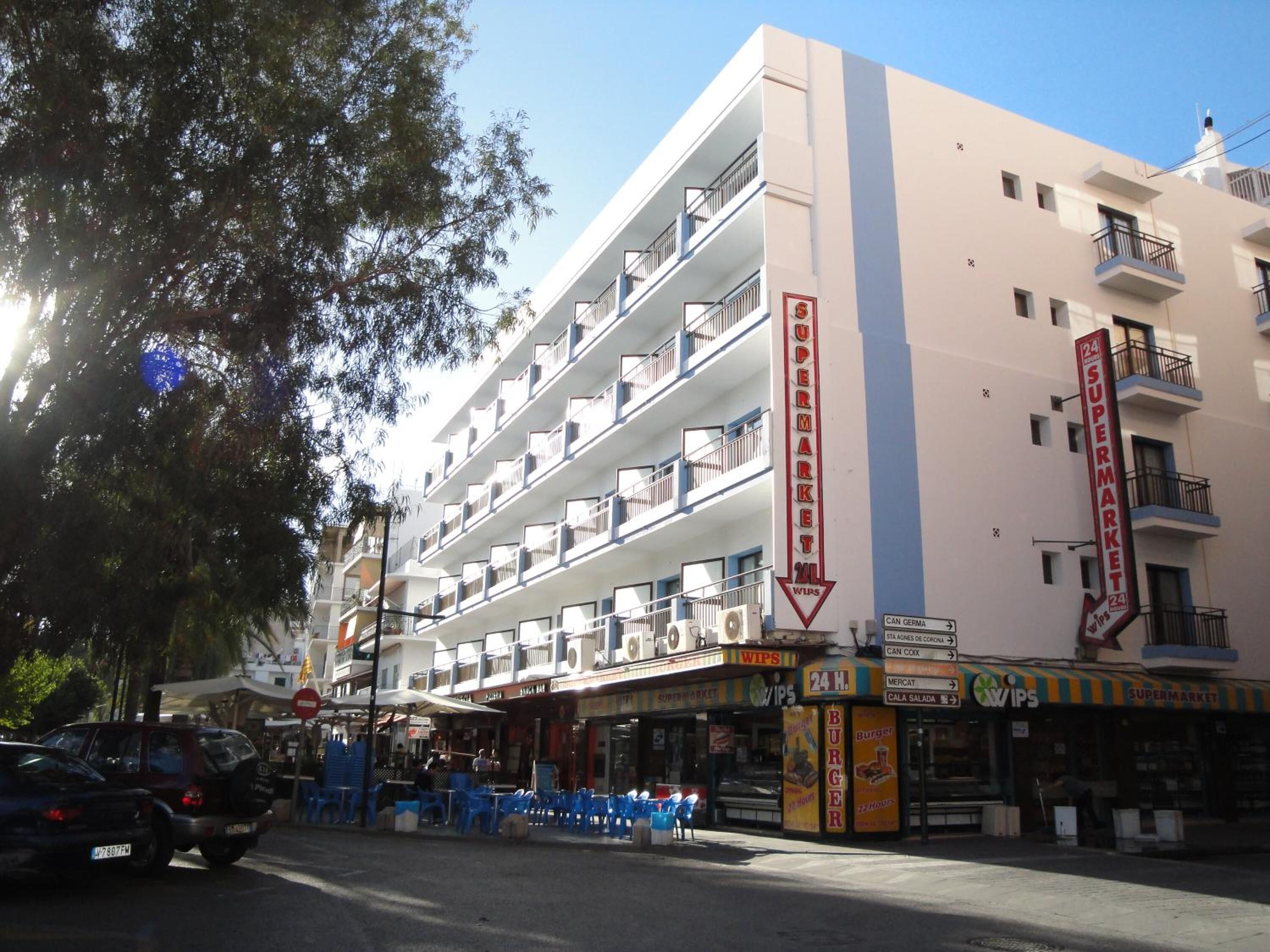 A multi-story building with a supermarket on the ground floor, balconies on each floor, and a sign indicating 24-hour service.