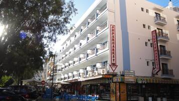 A multi-story building with a supermarket on the ground floor, balconies on each floor, and a sign indicating 24-hour service.