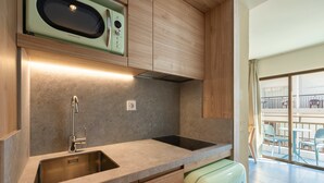 Cocina moderna con microondas integrado, pileta de acero inoxidable y alacenas de madera.