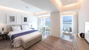 Quarto de hotel moderno com uma cama grande, um tapete estampado e vista para o mar pela varanda.