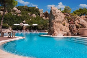 Una piscina al aire libre, sombrillas, sillones reclinables de piscina