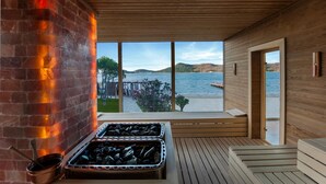 Una terraza de madera con chimenea de piedra, vista al mar y pared de madera.