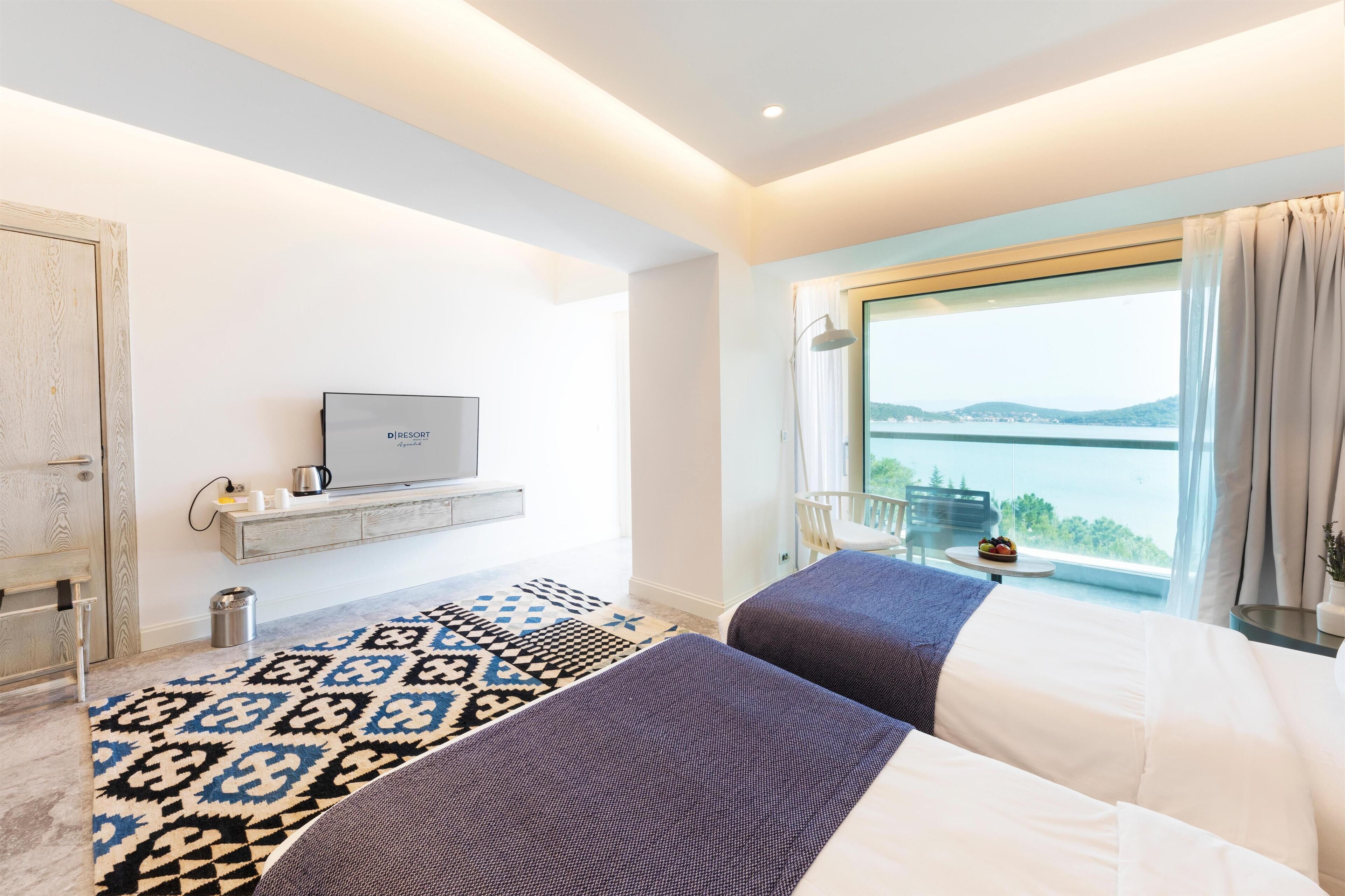 A modern hotel room with two beds, a TV, a balcony with a view, and a patterned rug.