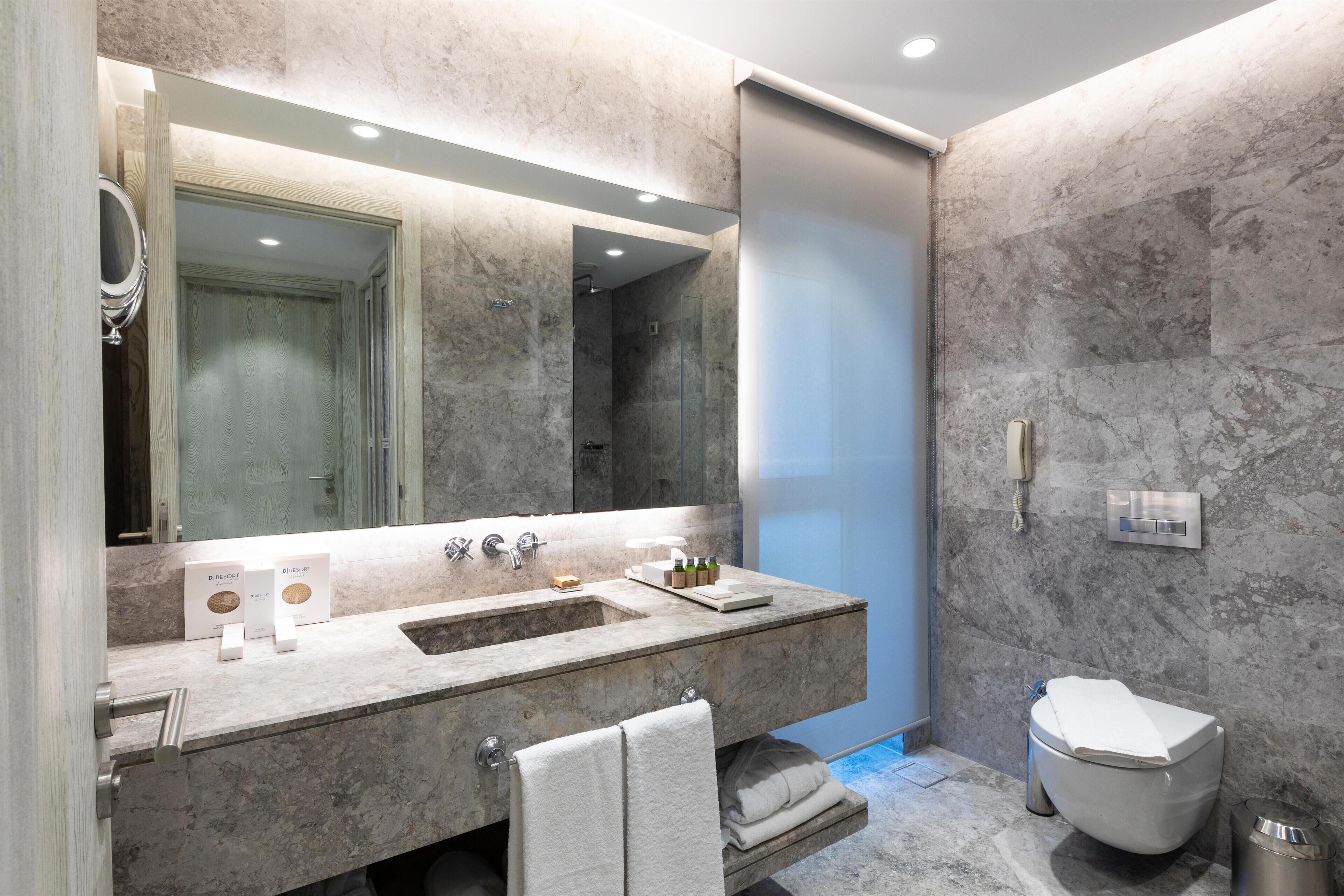 A modern bathroom with a large mirror, a sink, a toilet, and a shower area.