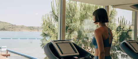 A person using a treadmill with a view of a lake and greenery outside.