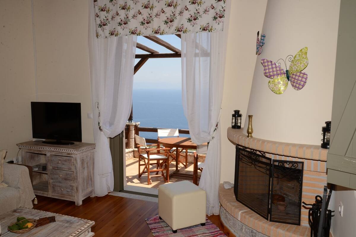 Ein gemütliches Wohnzimmer mit Fernseher, Kamin und Meerblick.