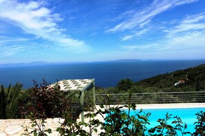 Een buitenzwembad, parasols bij het zwembad en ligstoelen