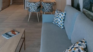 A modern living room with a sofa, patterned cushions, a dining table with chairs, and a kitchen area in the background. - The White Apartments by Ibiza Feeling - Adults Only (Sant Antoni de Portmany)