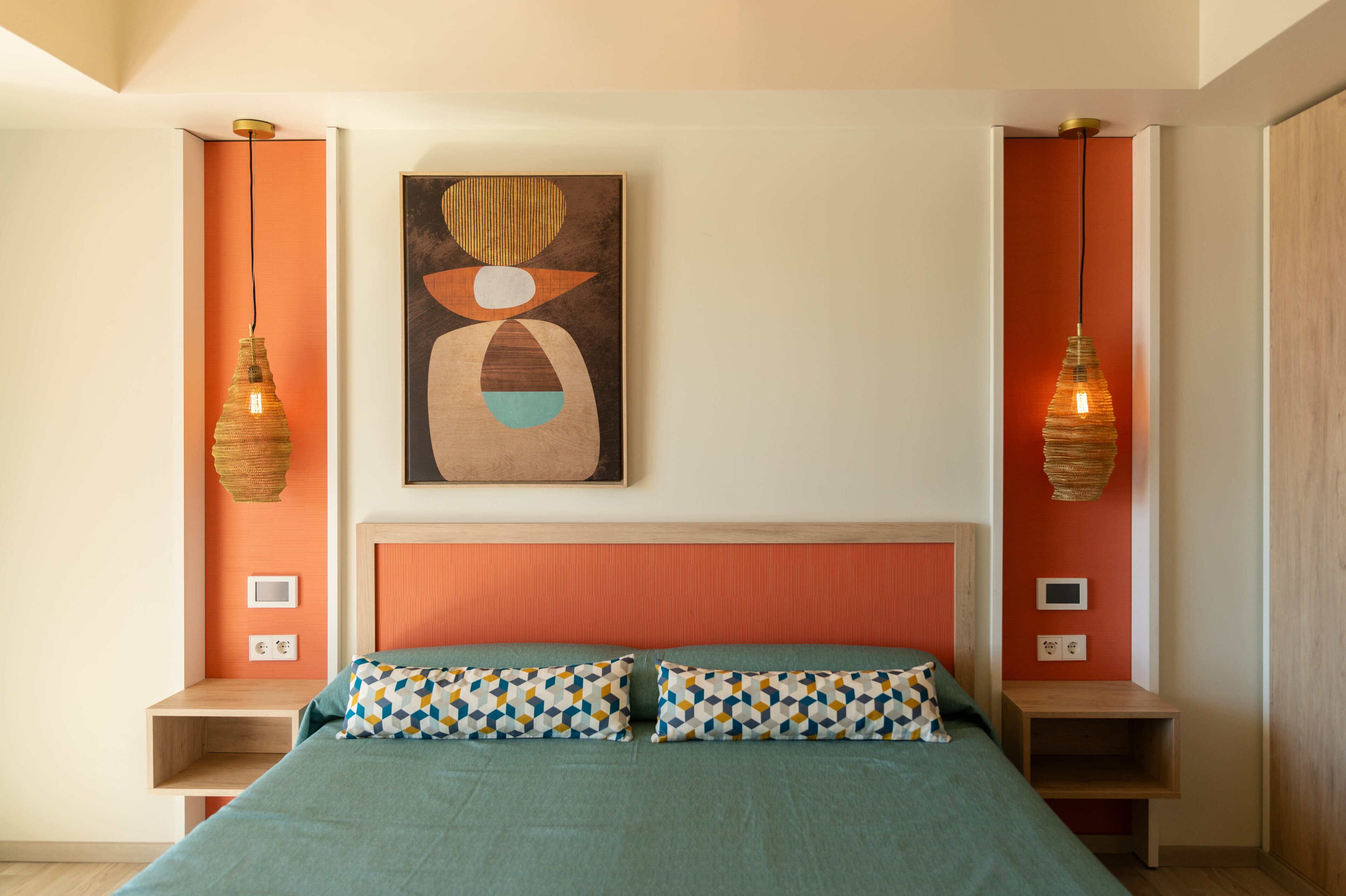 Un dormitorio con una cama, dos mesitas de noche, un cabecero y dos lámparas de pared.