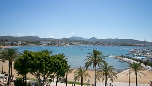A coastal marina with boats, a sandy beach, and palm trees. - The White Apartments by Ibiza Feeling - Adults Only (Sant Antoni de Portmany)