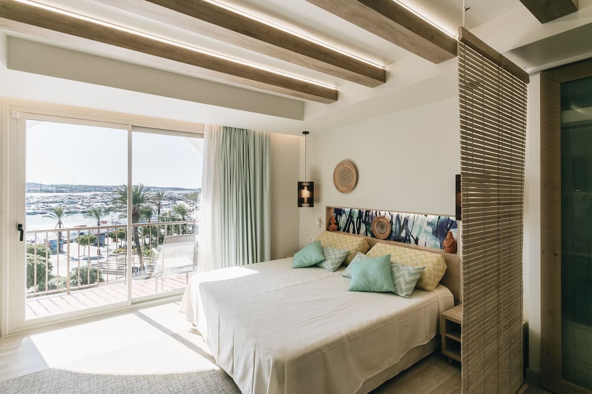 Une chambre avec un grand lit, une vue sur la ville et un balcon.