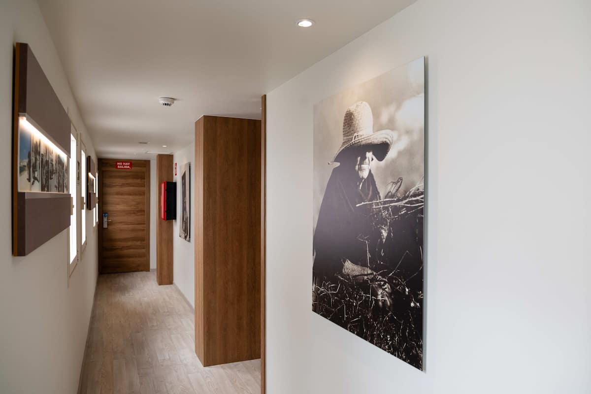 Un couloir orné de tableaux encadrés, une porte en bois et une grande photographie en noir et blanc représentant une personne jouant de la guitare.