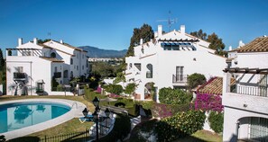 Una villa blanca con piscina, rodeada de jardines exuberantes y vistas despejadas a las montañas.
