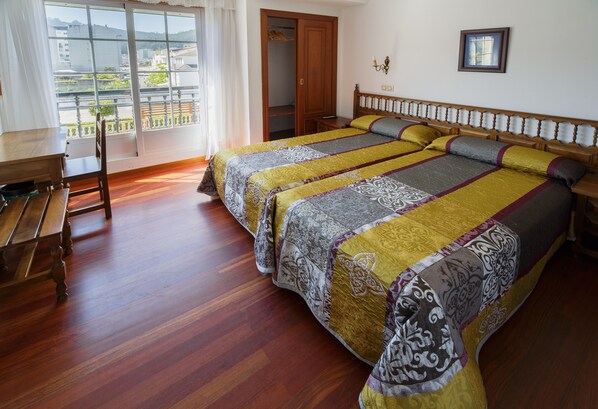A hotel room with a large bed, wooden flooring, a desk, and a view of the city through a large window. - Hotel As Areas I (Viveiro)