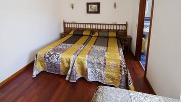 Un dormitorio con una cama de madera, un edredón estampado y un cuadro enmarcado en la pared.