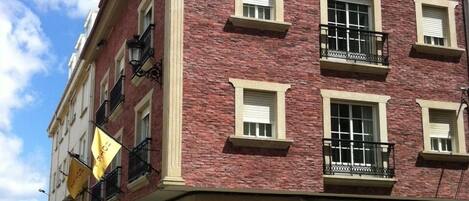 Un hotel de varios pisos con fachada de ladrillo, balcones y un letrero que dice "AS AREAS".