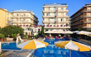 A hotel with multiple balconies, a swimming pool, and outdoor umbrellas. - Hotel Sirenetta (Jesolo)