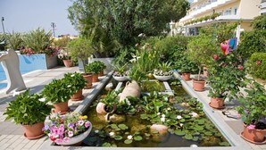 A rooftop garden with a small pond surrounded by terracotta pots with various plants and flowers. - Hotel Sirenetta (Jesolo)