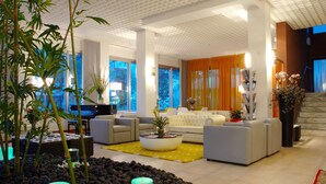 A spacious living room with a piano, sofas, and a coffee table. - Hotel Sirenetta (Jesolo)