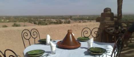 A dining table set outdoors with a view of a desert landscape.