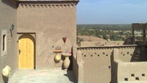 A traditional building with a wooden door, a small courtyard, and a view of the surrounding landscape. - Dar Panorama (Skoura)