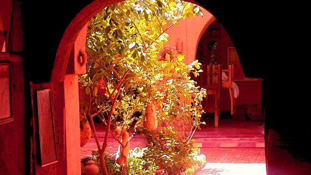 An arched doorway leading to a courtyard with a tree and a small fountain. - Dar Panorama (Skoura)