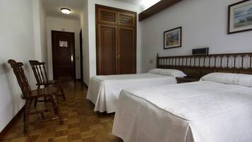 Habitación de hotel con dos camas, suelo de madera, armario y un cuadro en la pared.