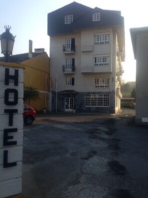 A multi-story hotel with a flat facade, balconies, and a parking area. - Hotel As Areas II (Viveiro)