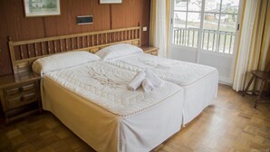 Una cama doble con cabecera de madera, una mesita de noche y una ventana con vistas a edificios.
