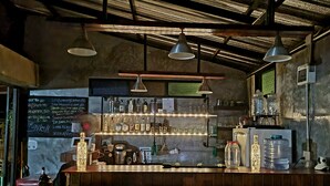 Un espace bar avec un tableau affichant le menu, des étagères remplies de bouteilles, une machine à café et un distributeur d’eau.