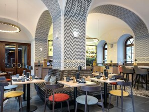 A restaurant with high arched ceilings, patterned walls, and a bar area. - Mercure Vienna First (Vienna)