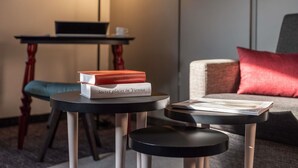 Een moderne woonkamer met een ronde zwarte tafel, een rood boek getiteld 'Geheime plekken in Wenen', en een laptop op een houten tafel.