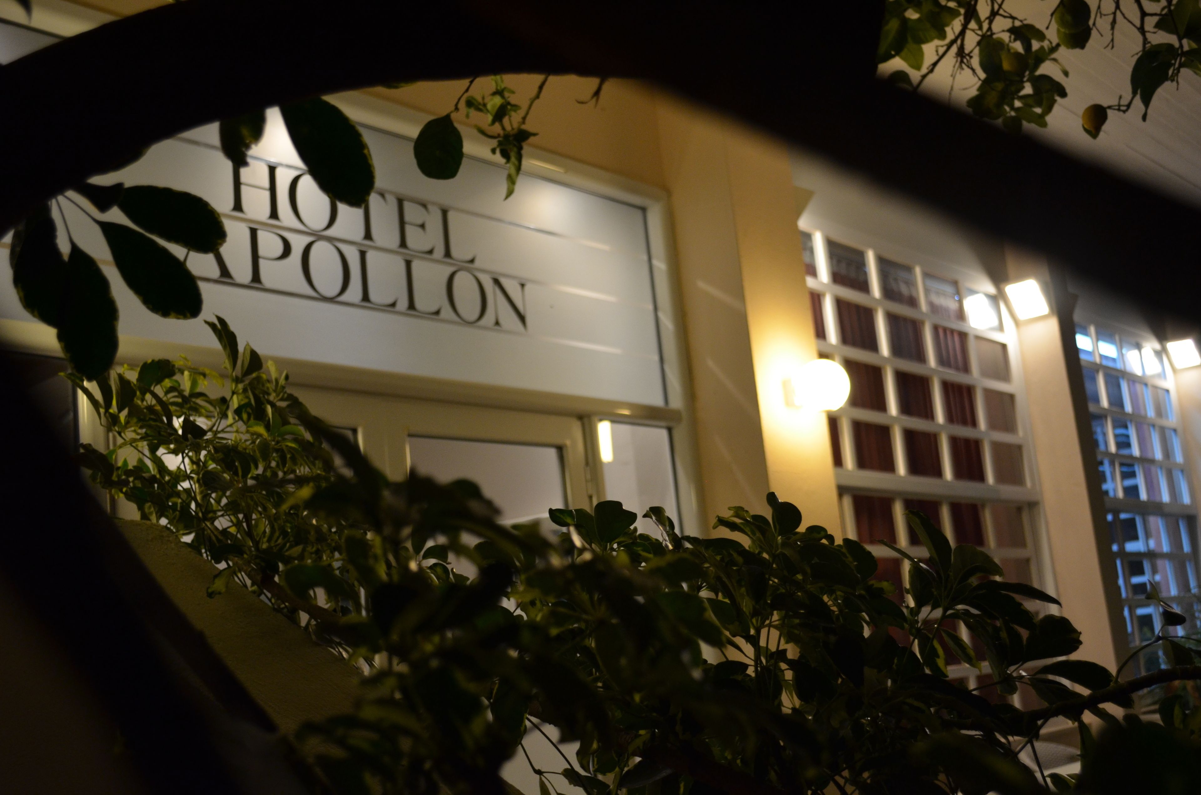 A hotel sign with the name "HOTEL APOLLON" and a window with curtains.