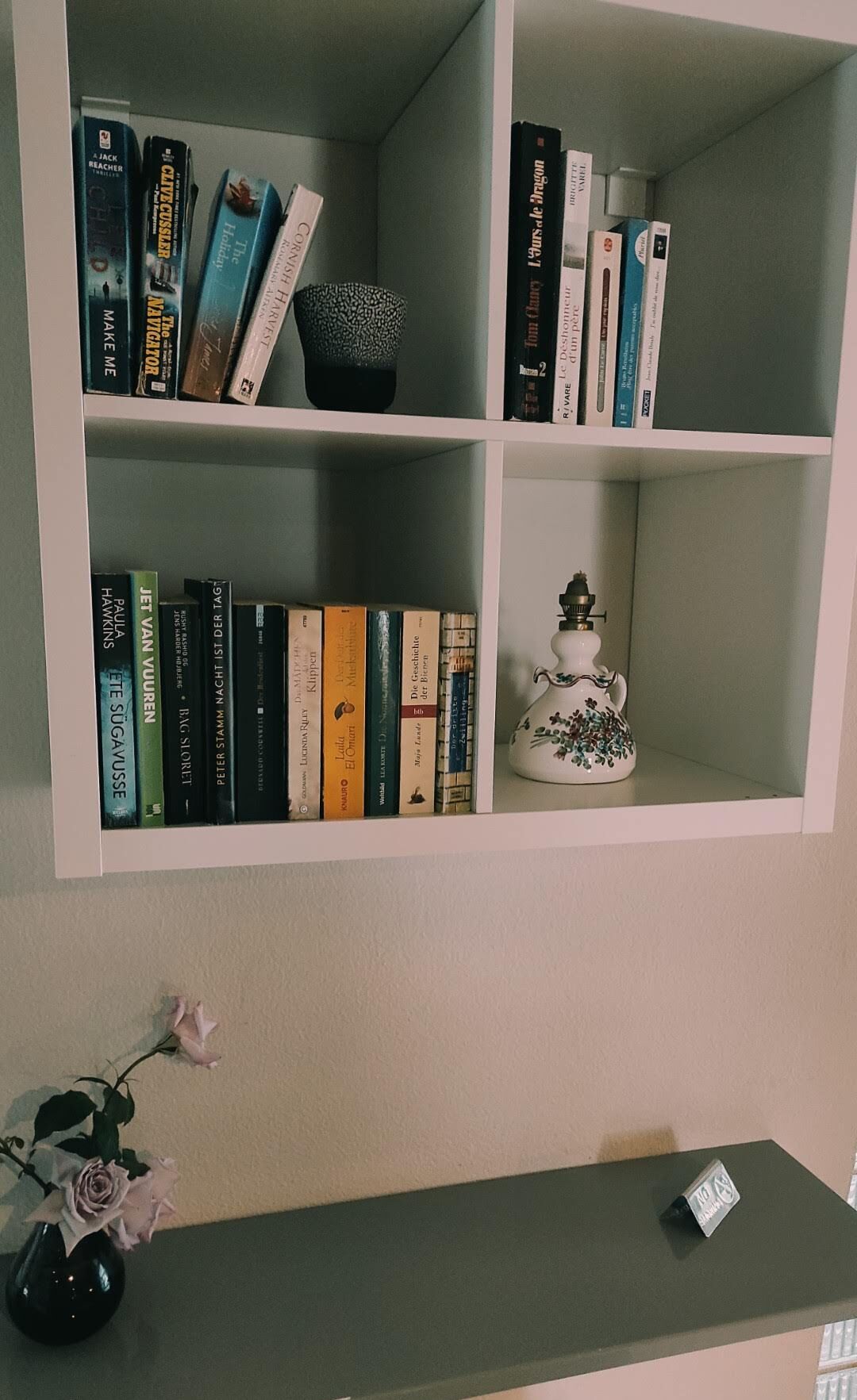 A bookshelf with books and a decorative ceramic pitcher.