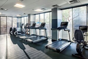 Un gimnasio con cintas de correr, elípticas y bicicletas estáticas.
