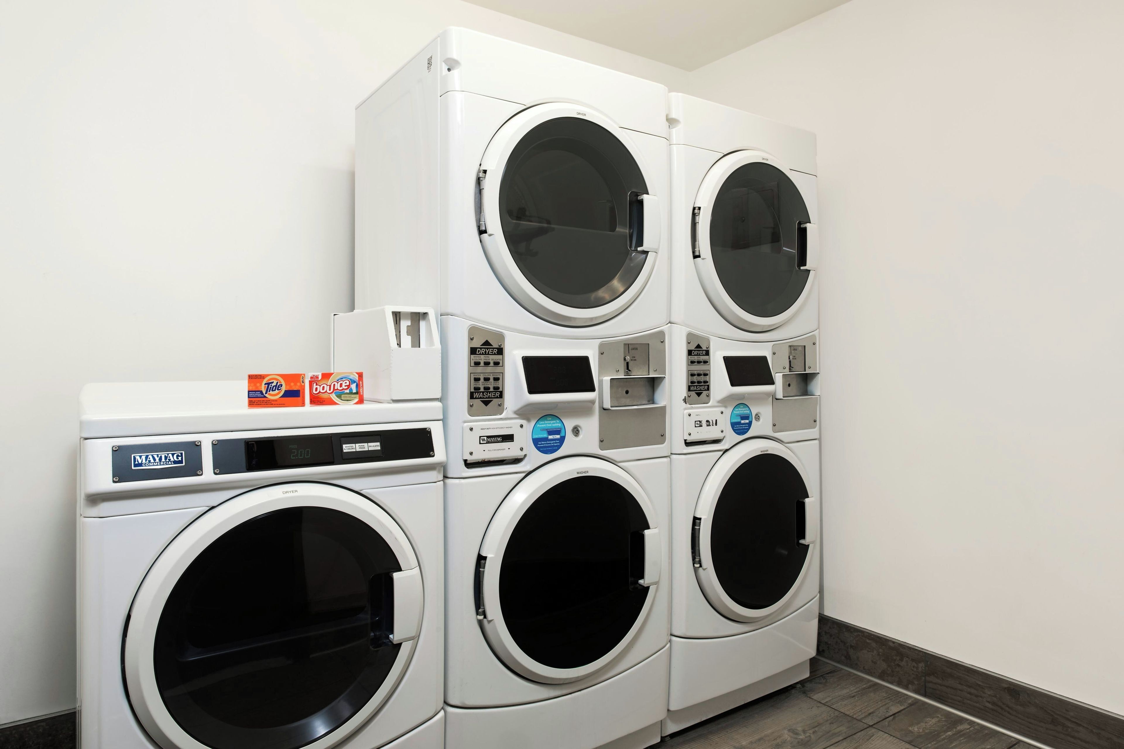 A row of stacked laundry machines in a commercial setting.