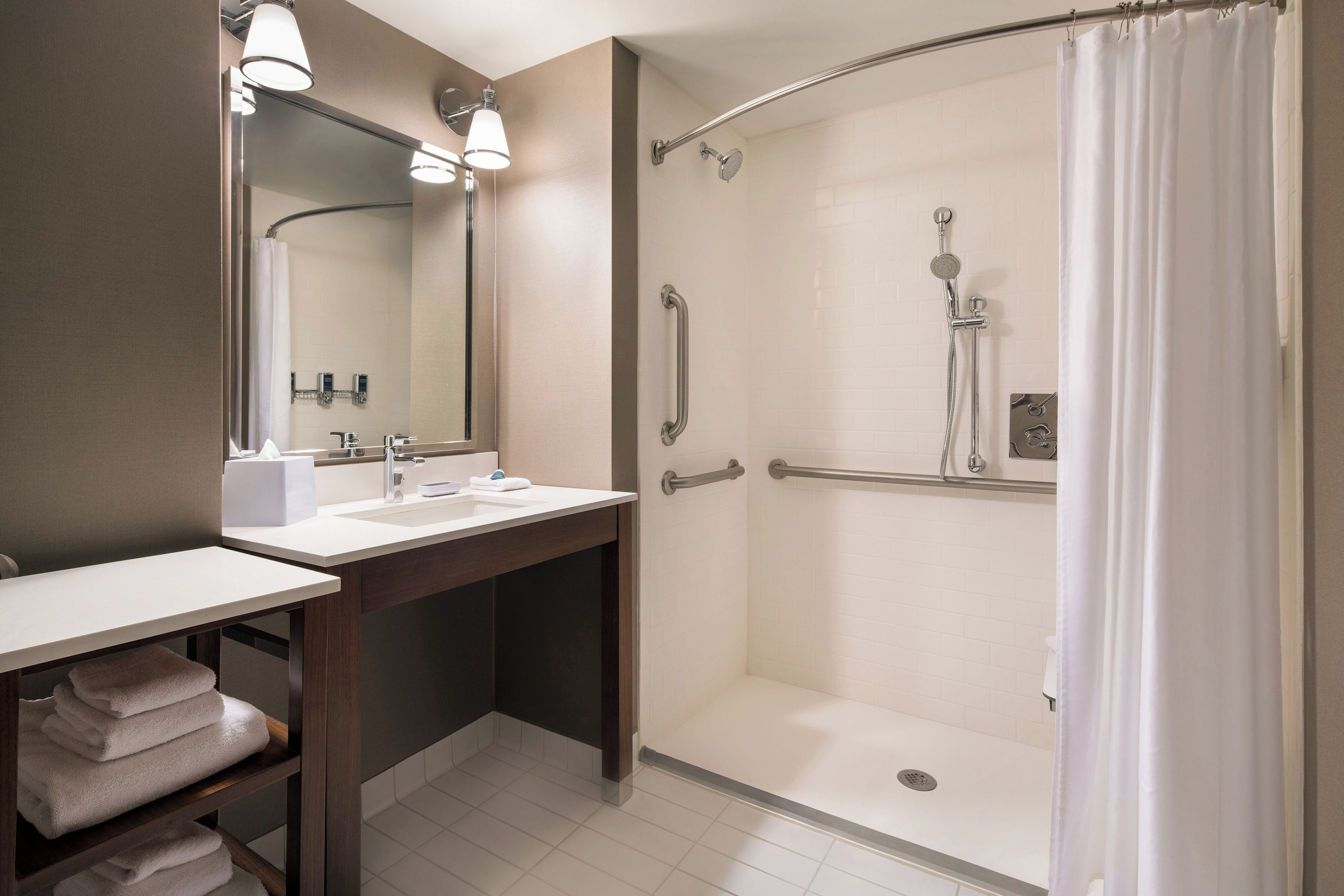 Un baño con ducha, lavamanos y espejo.