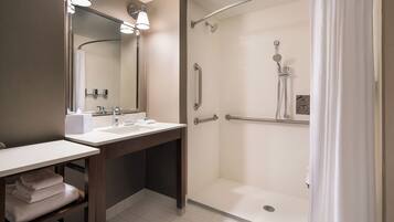 Un baño con ducha, lavamanos y espejo.