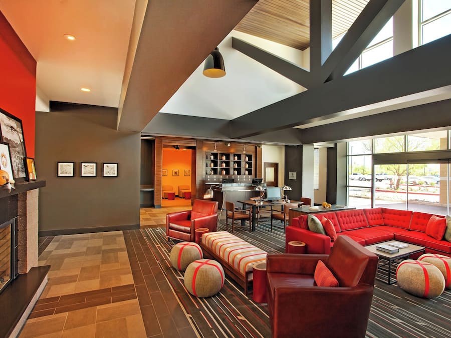 A modern hotel lobby with a fireplace, seating area, and a view of the street.