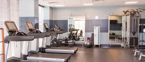 Un gimnasio con cintas de correr, elípticas y equipos de pesas.