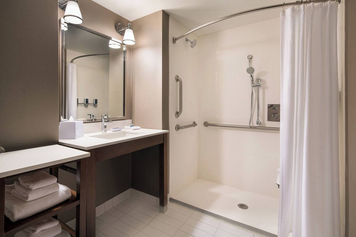 Un baño moderno con ducha, lavamanos y espejo.