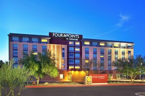 Un hotel de varios pisos con un letrero llamativo que dice 'FOUR POINTS BY SHERATON'.
