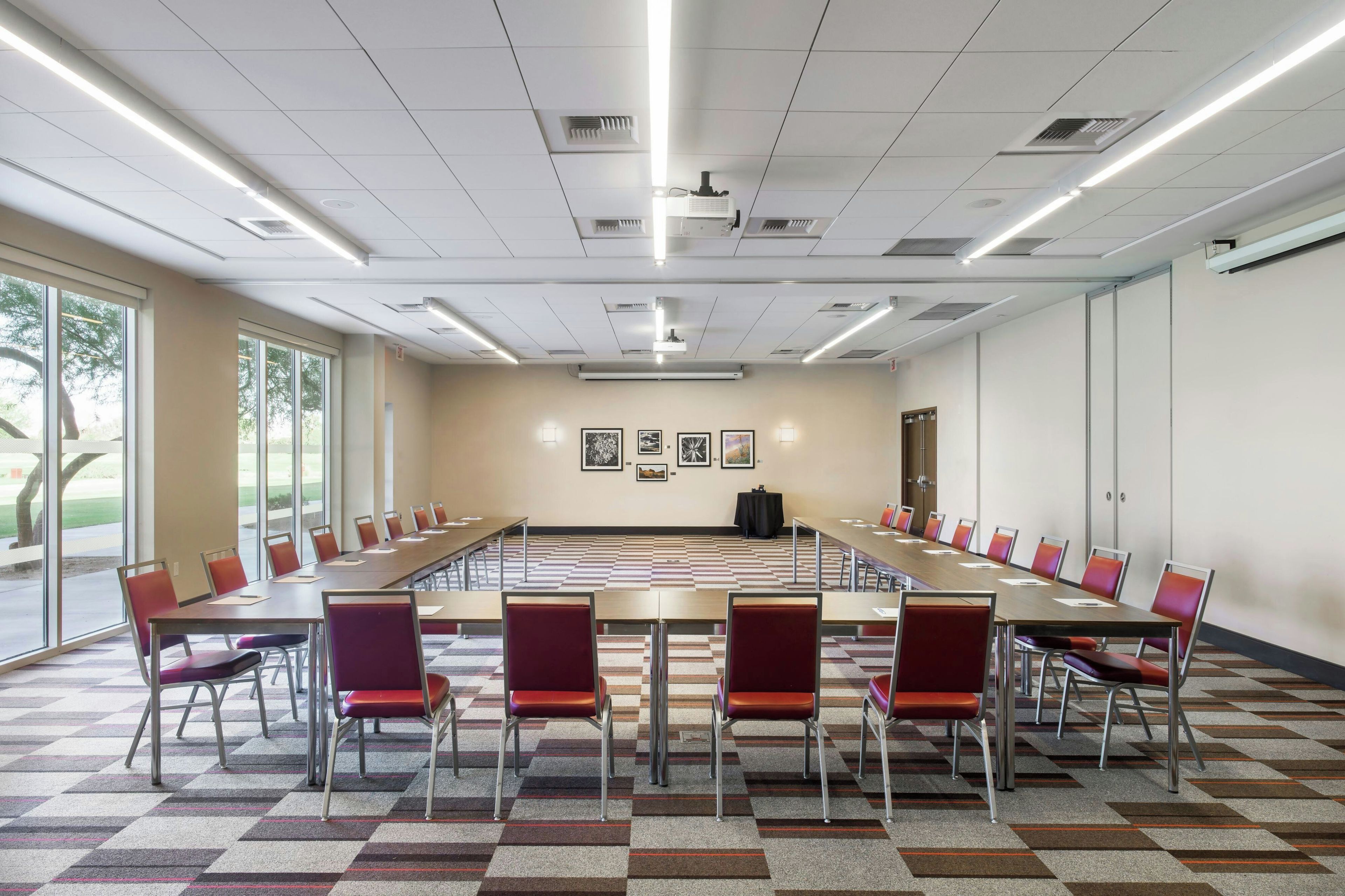 A conference room with a long table, chairs, and framed pictures on the wall.